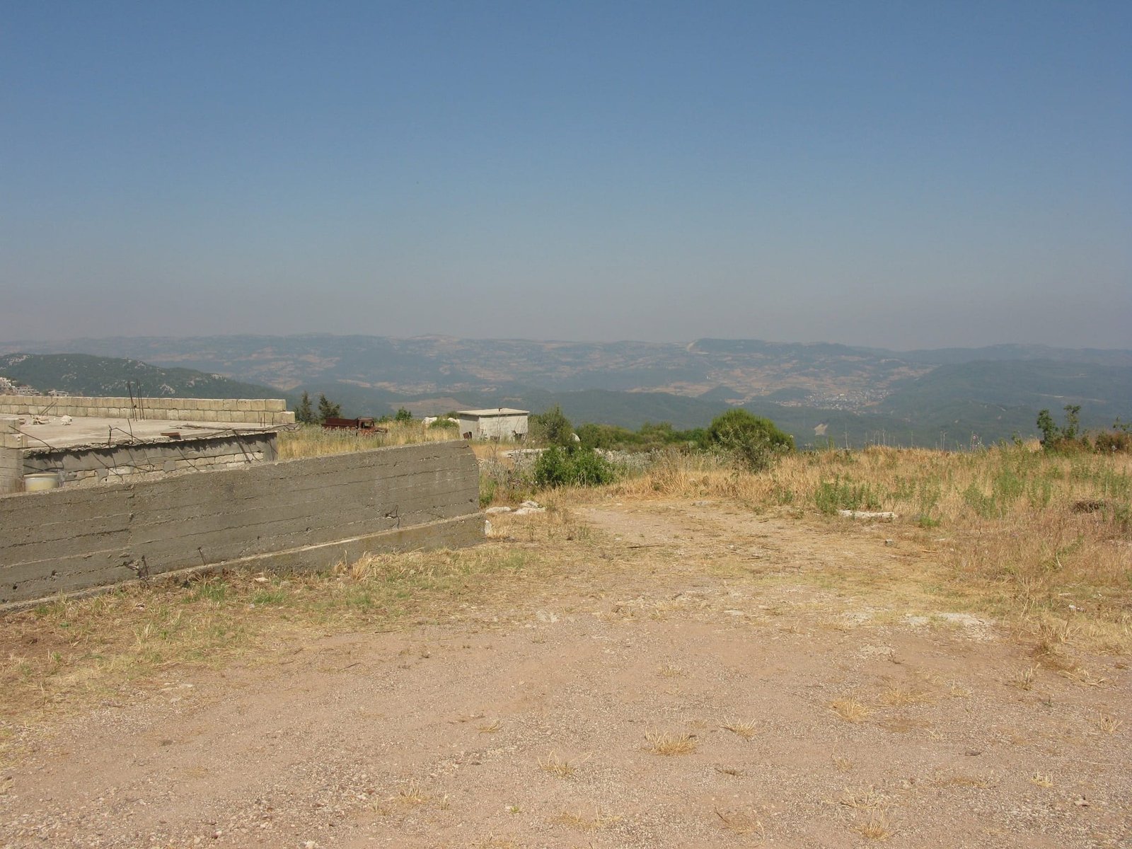 The eastern ground, graded and unbuilt, with the retaining wall already poured.